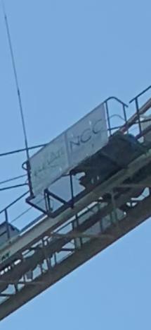 Crane with "NCC" sign against blue sky.