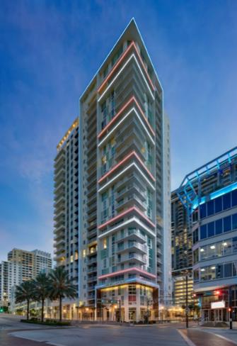 Modern skyscraper with illuminated exterior at dusk.