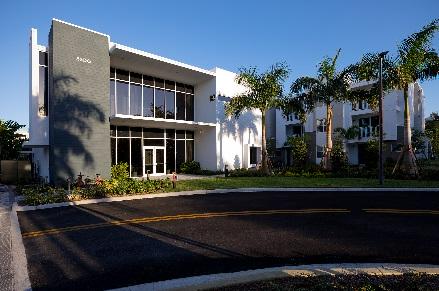 Modern building with palm trees and driveway.