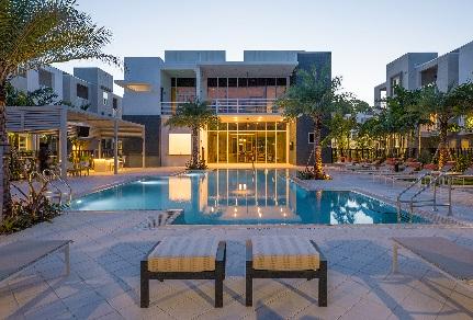 Modern apartment complex with illuminated swimming pool.