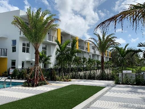 Modern apartments with palm trees and pool.