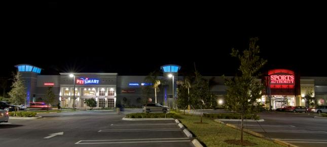 Shopping center at night with illuminated signs.