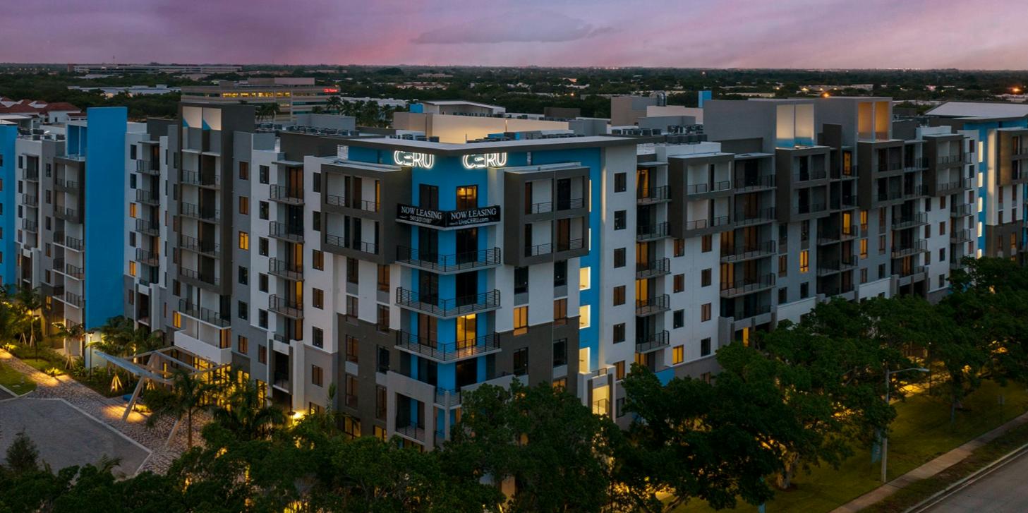 Modern apartment building at dusk, illuminated windows.