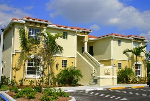 Yellow apartment building with palm trees outside.