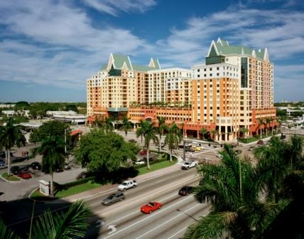 Urban building complex with palm trees and road.