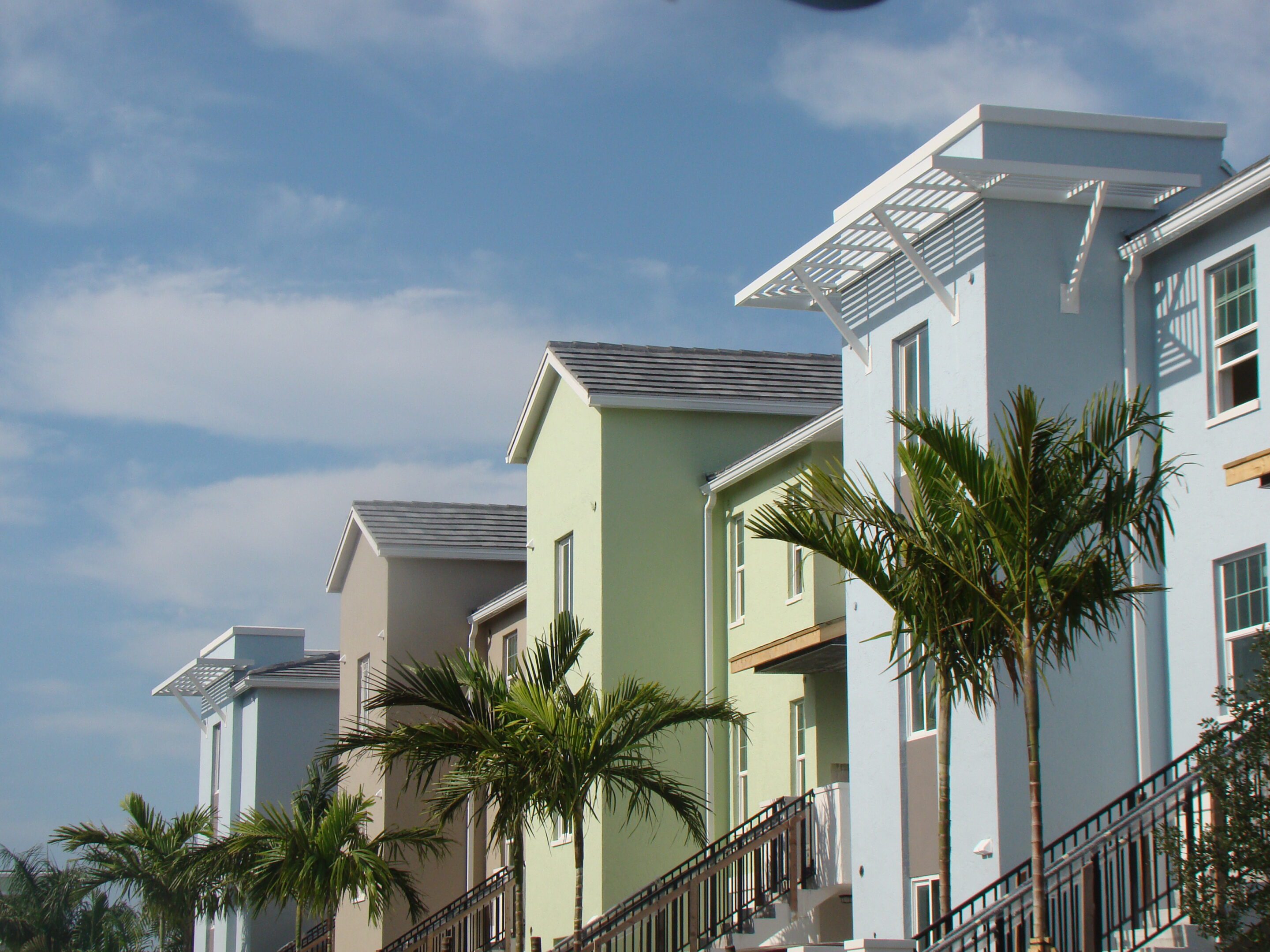 Colorful row of modern houses with palm trees under a bright sky.