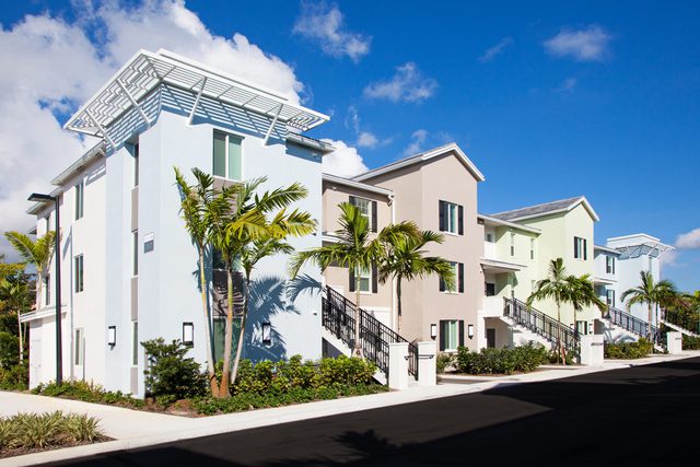 Modern residential buildings with palm trees under a bright blue sky.