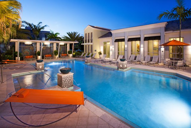 Luxurious outdoor pool area with lounge chairs and warm lighting at dusk.