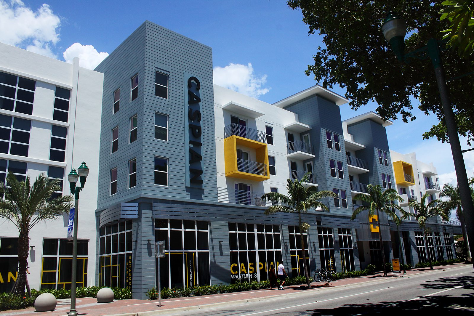 Modern apartment building with blue and gray exterior and yellow balcony accents.