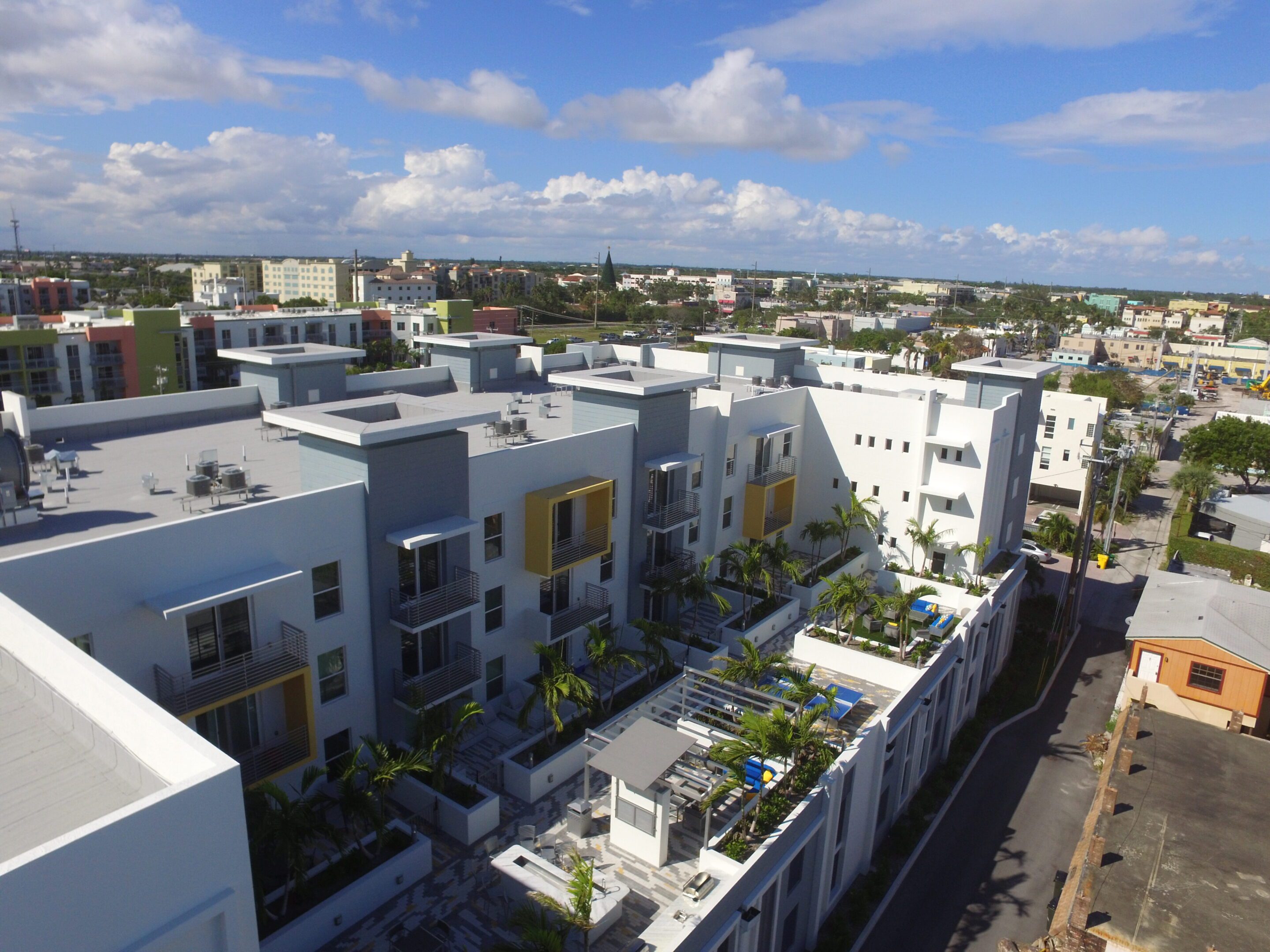 Aerial view of modern residential buildings with rooftop terraces under a blue sky.