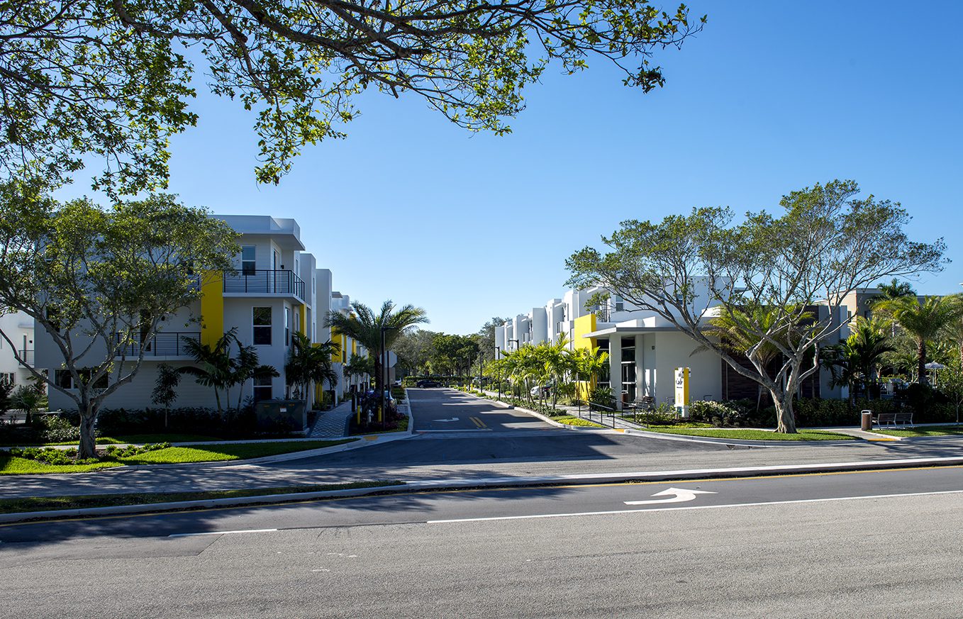 Residential street with modern houses under a clear blue sky.