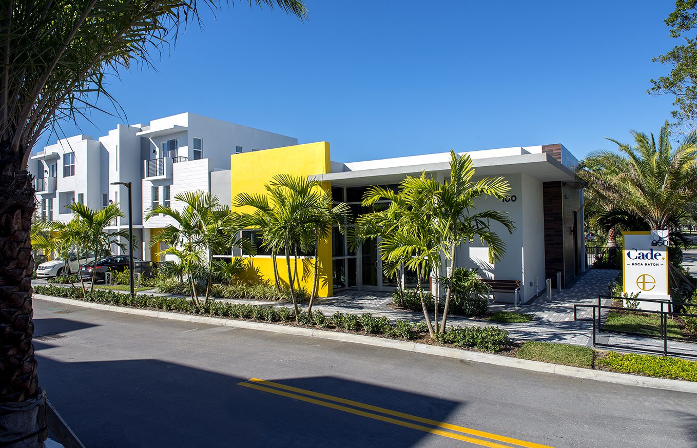 Modern house with yellow accent wall and tropical landscaping.