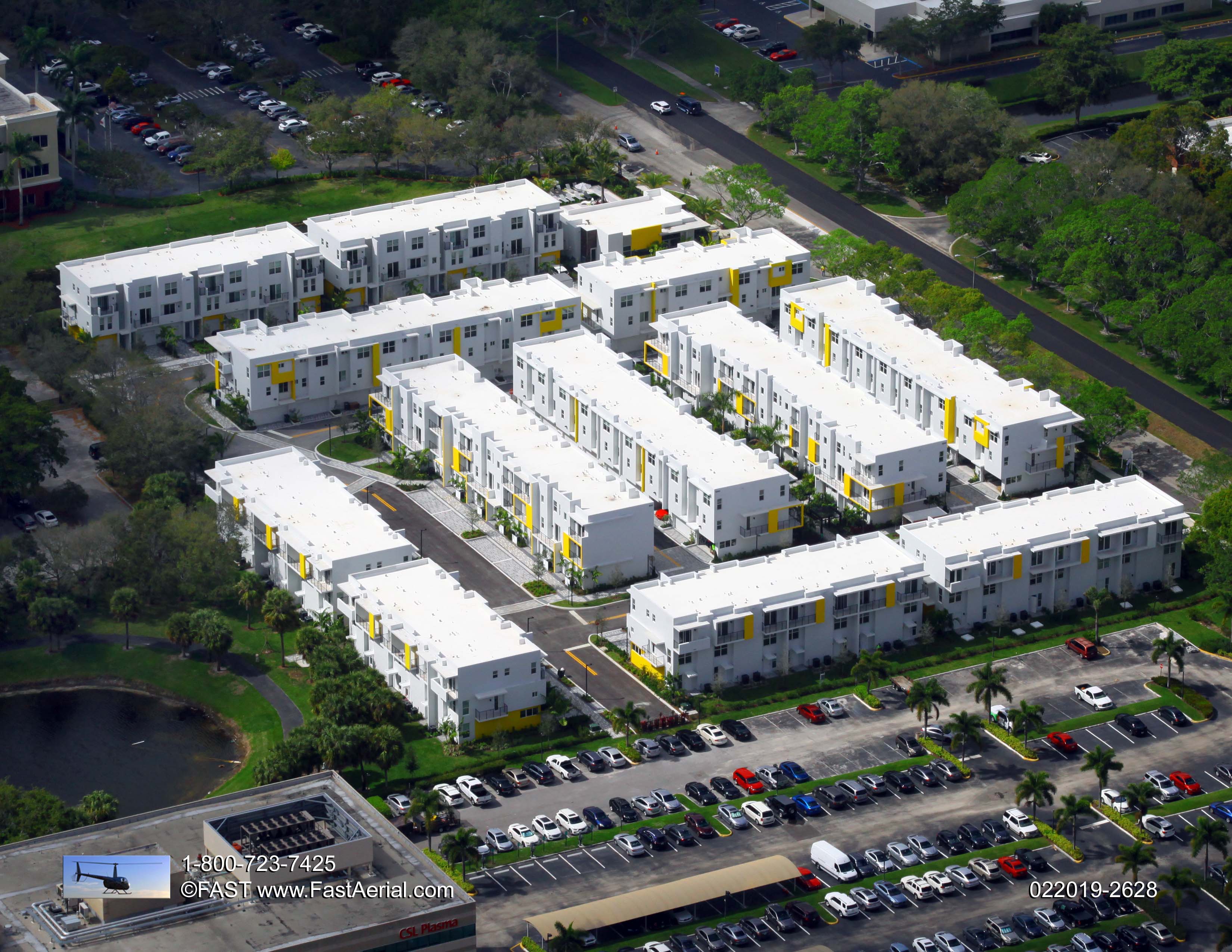 Aerial view of a modern residential complex with white buildings and green spaces.