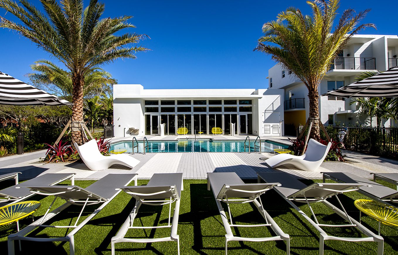 Luxurious poolside seating at a modern villa under clear blue skies.