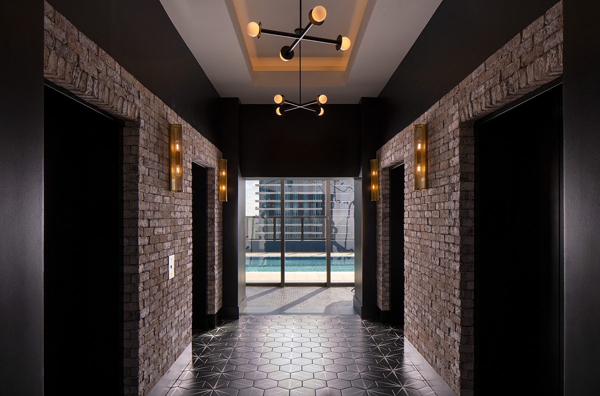 Modern hallway with brick walls and stylish lighting leading to a glass door.