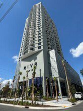 Tall modern building with 'Riva Residences' signage under a blue sky.