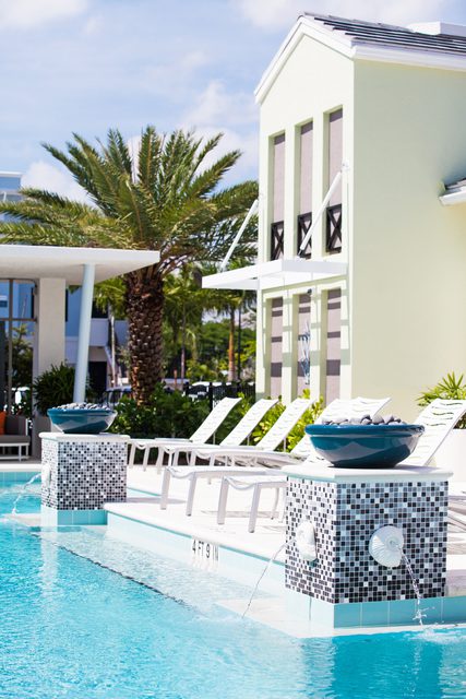 Modern outdoor pool area with lounge chairs and palm trees.