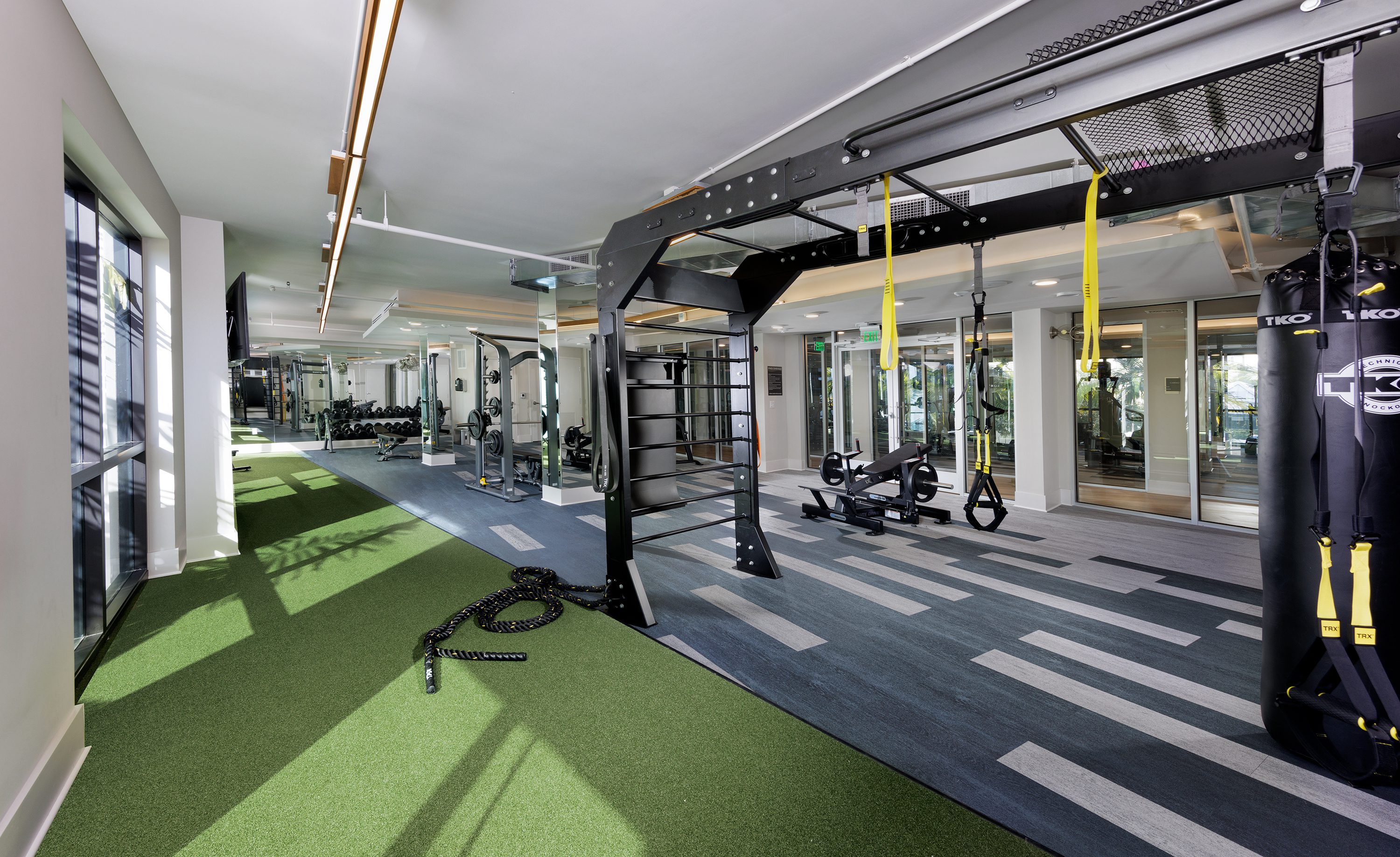 Modern gym area with various workout equipment and artificial turf.