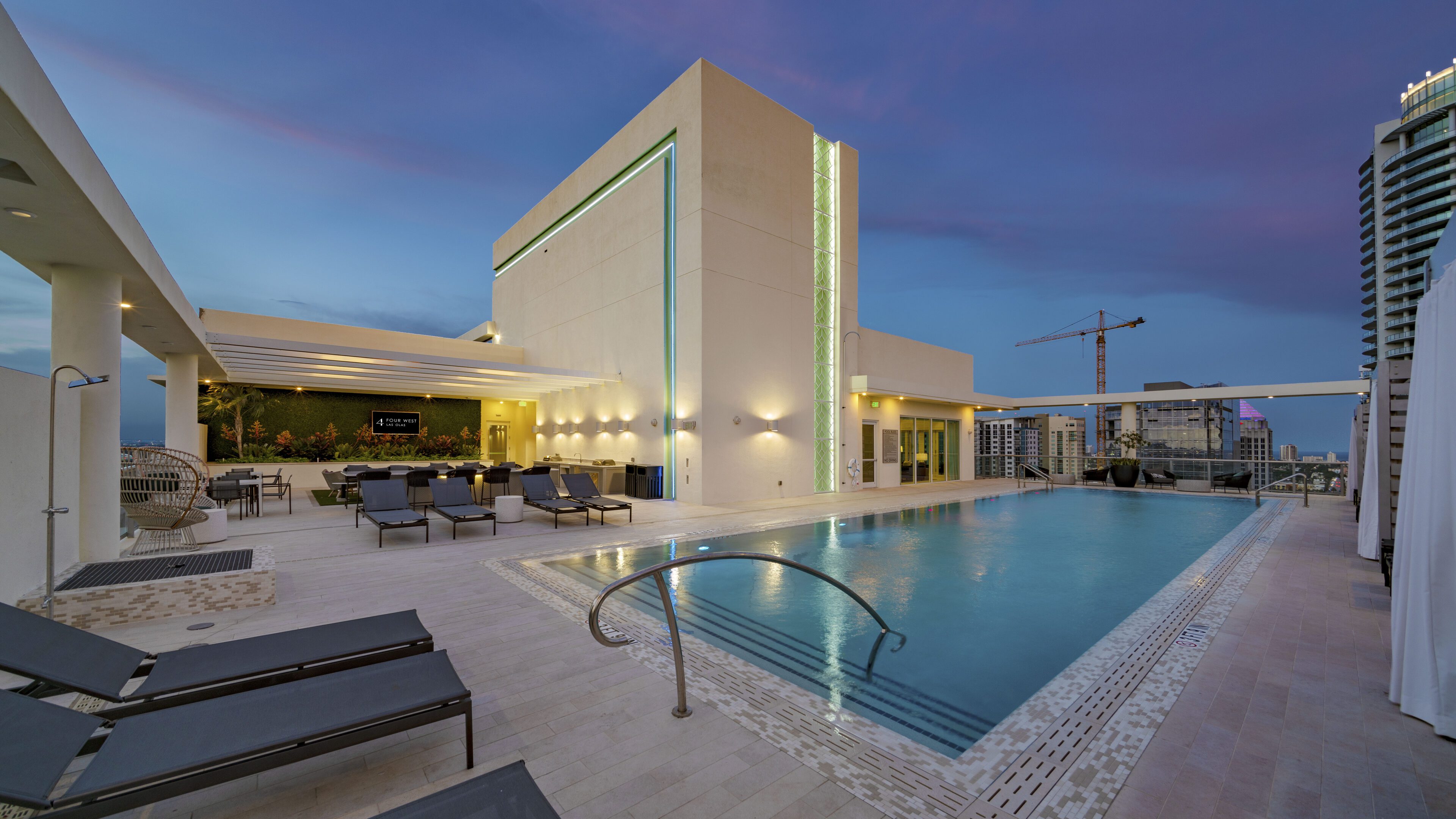 Modern hotel pool area at dusk with lounge chairs and ambient lighting.