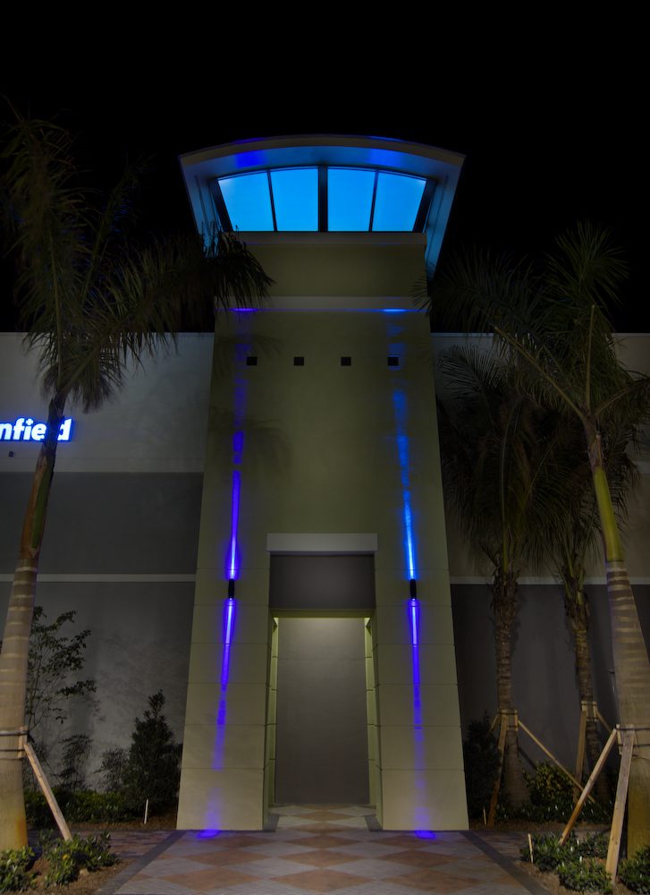 A modern building tower illuminated with blue lights at night.