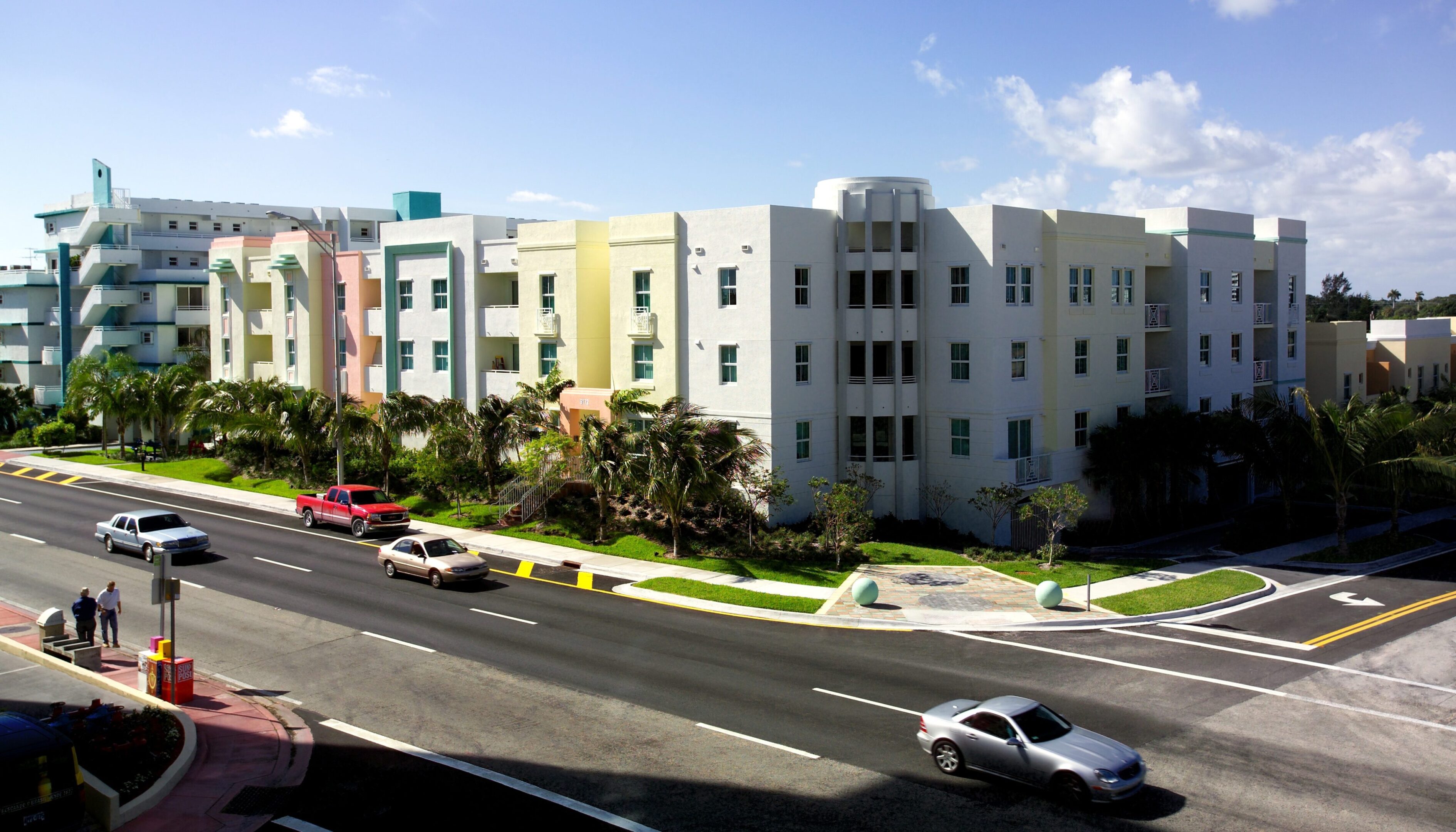 Modern apartment buildings with colorful facades along a sunny street.