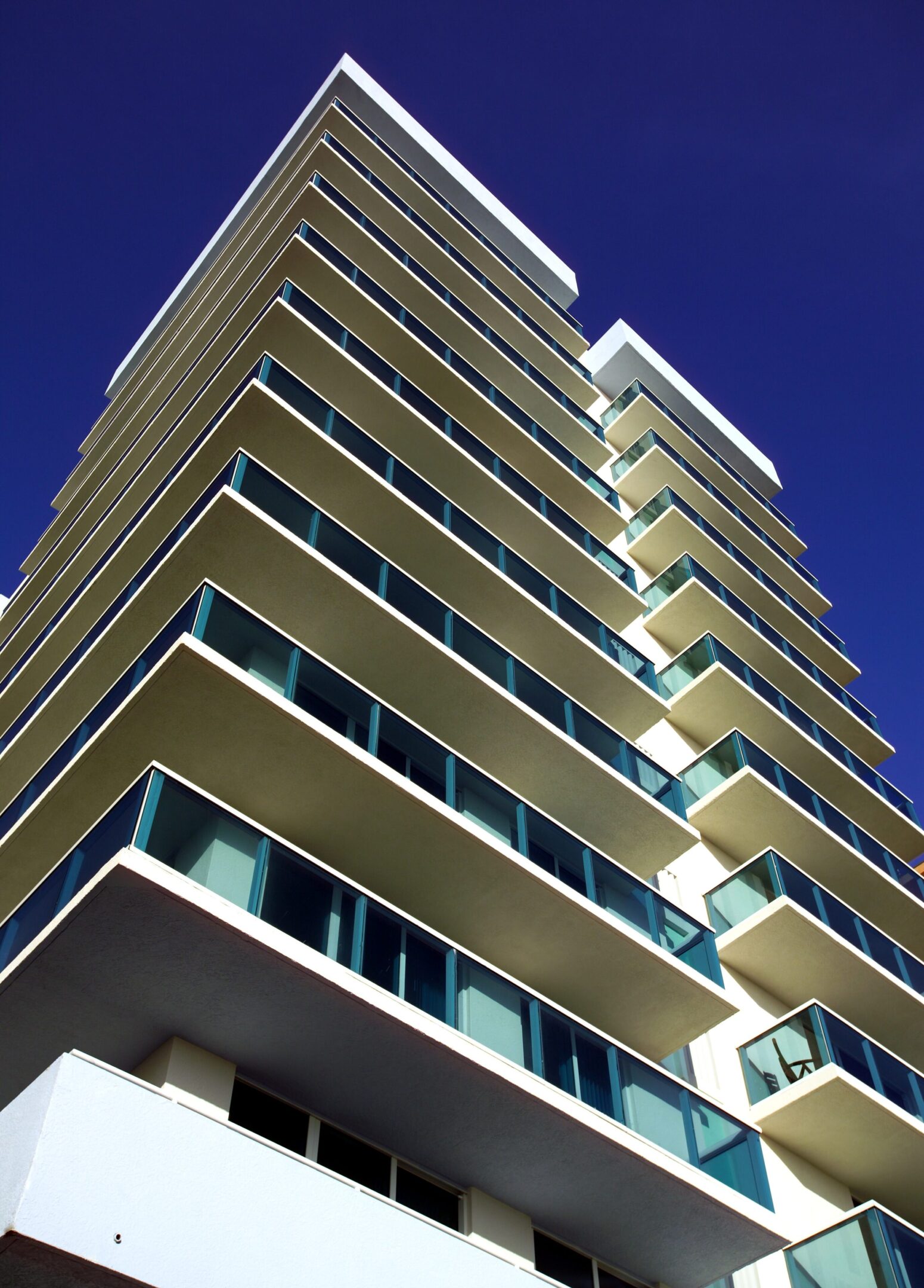 Modern high-rise residential building with balconies against a clear blue sky.