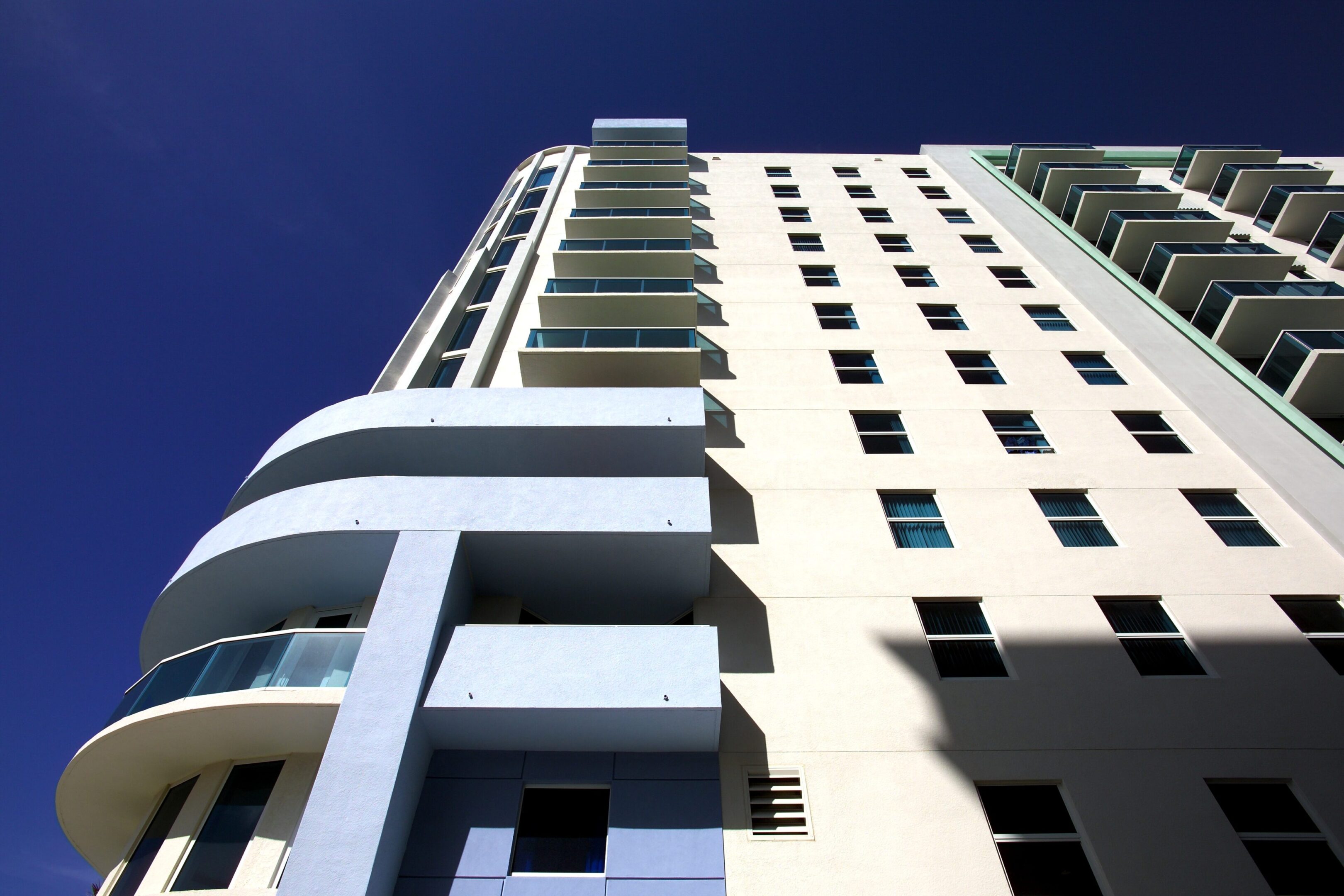 Low-angle view of a modern white building against a clear blue sky.