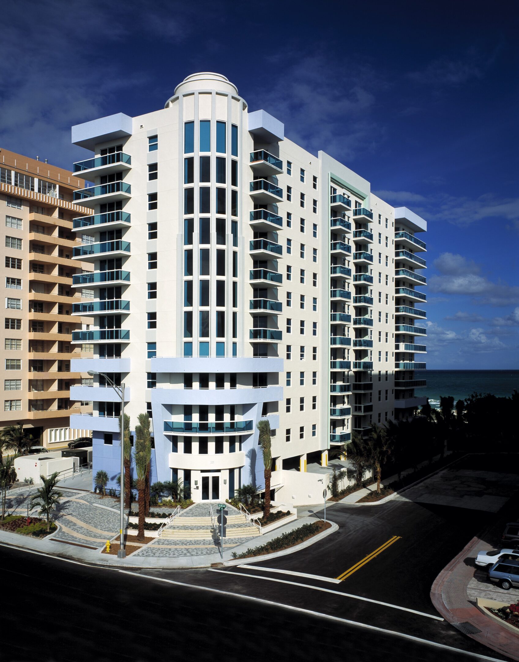 Modern white apartment building near the ocean under a clear blue sky.