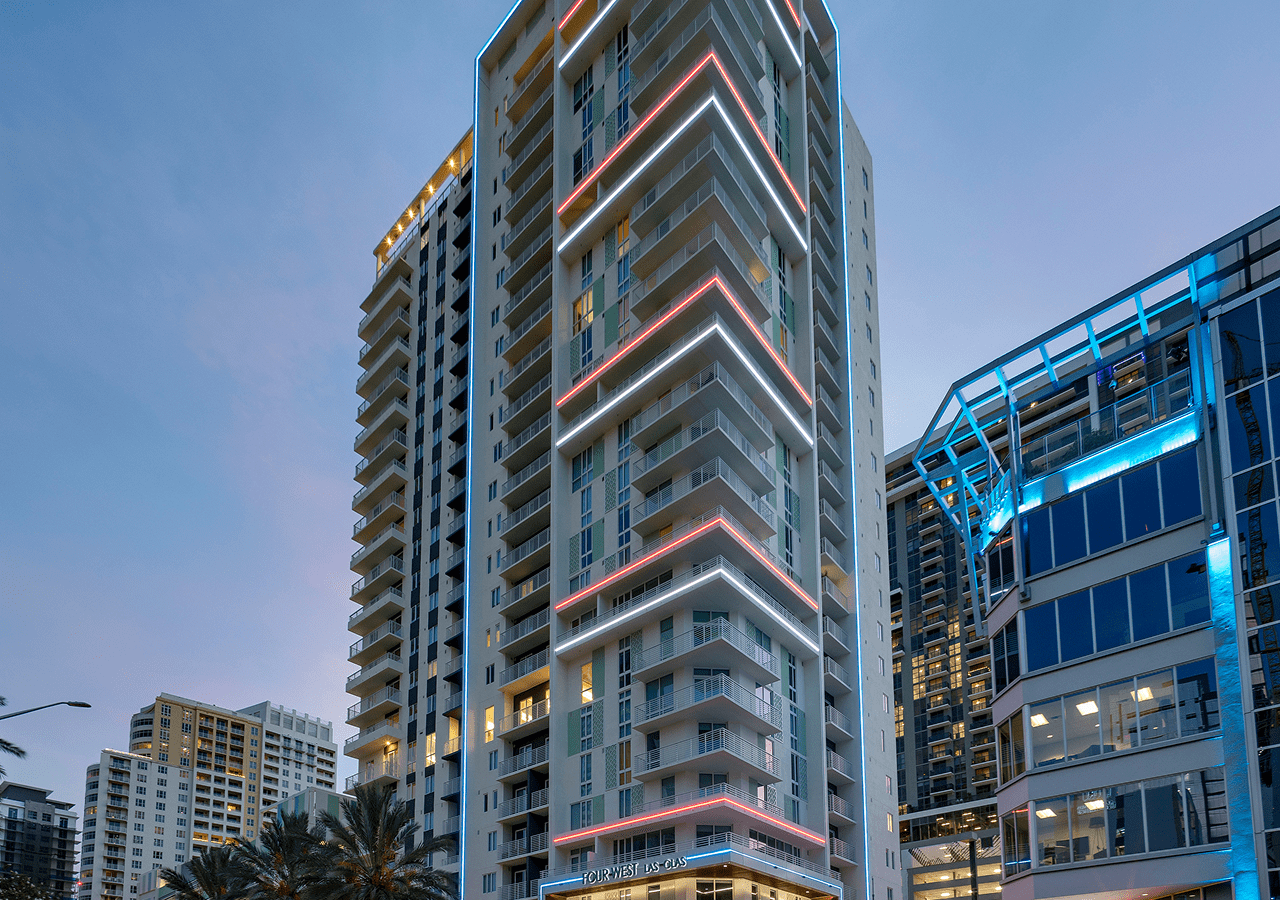 Modern high-rise residential buildings at dusk with illuminated balconies.