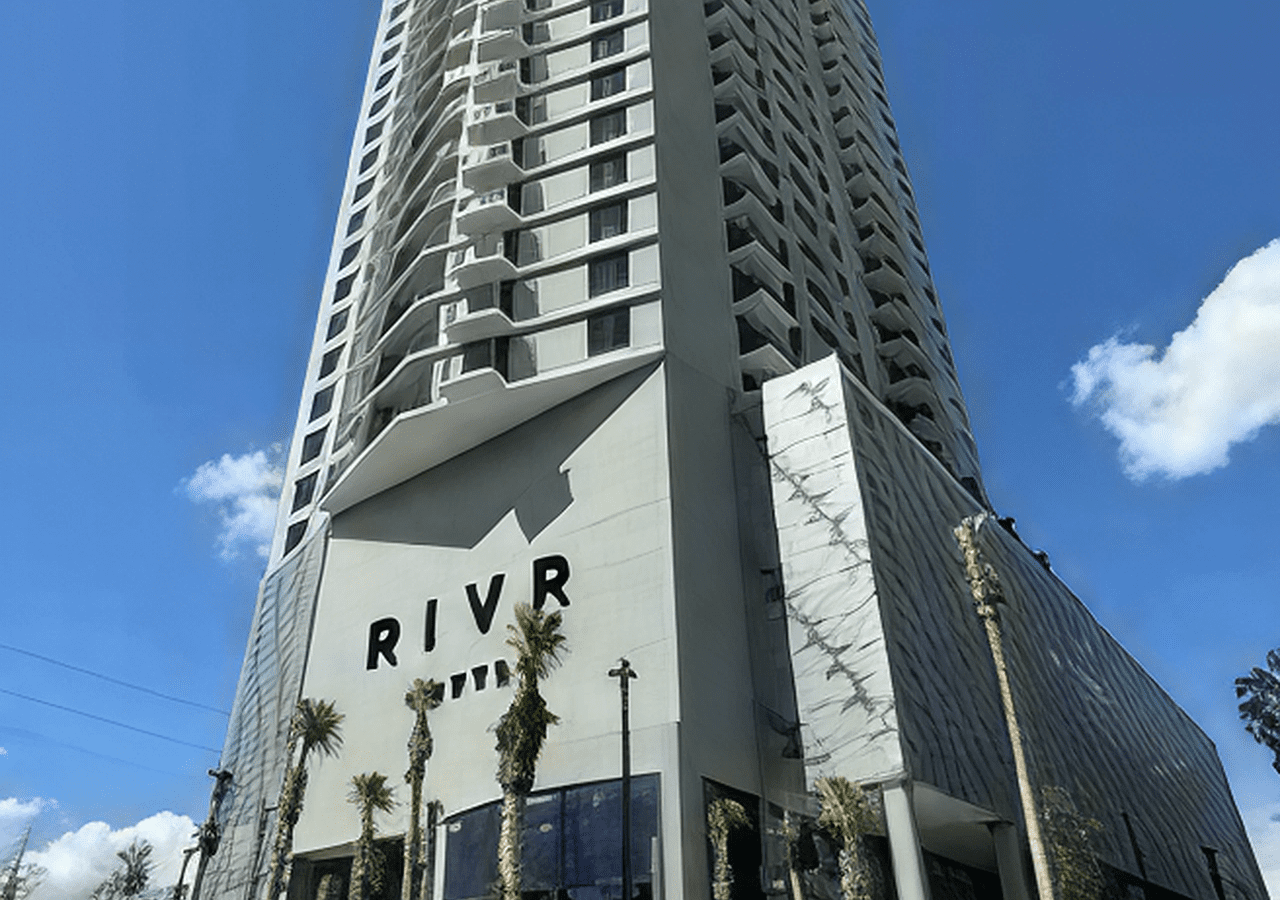 Tall modern building with RIVR sign against blue sky.