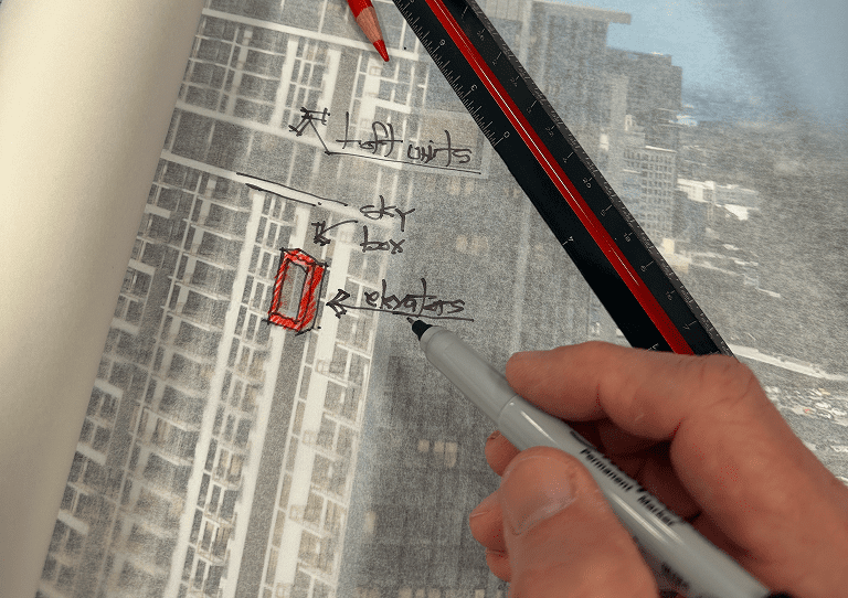 Hand writing notes on a transparent surface with a cityscape background.