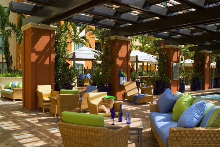 Cozy outdoor lounge with colorful cushions and shaded seating under a pergola.