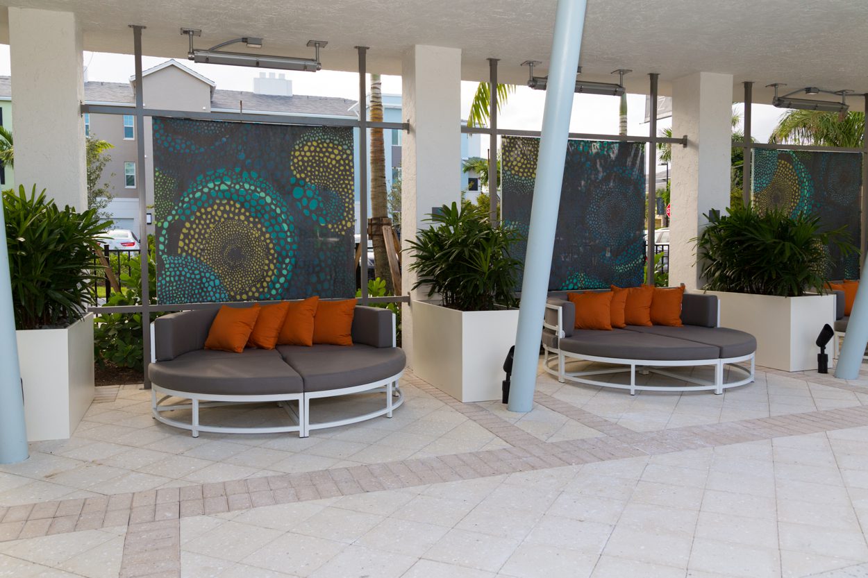 Two round outdoor lounge beds with orange cushions under a covered patio.