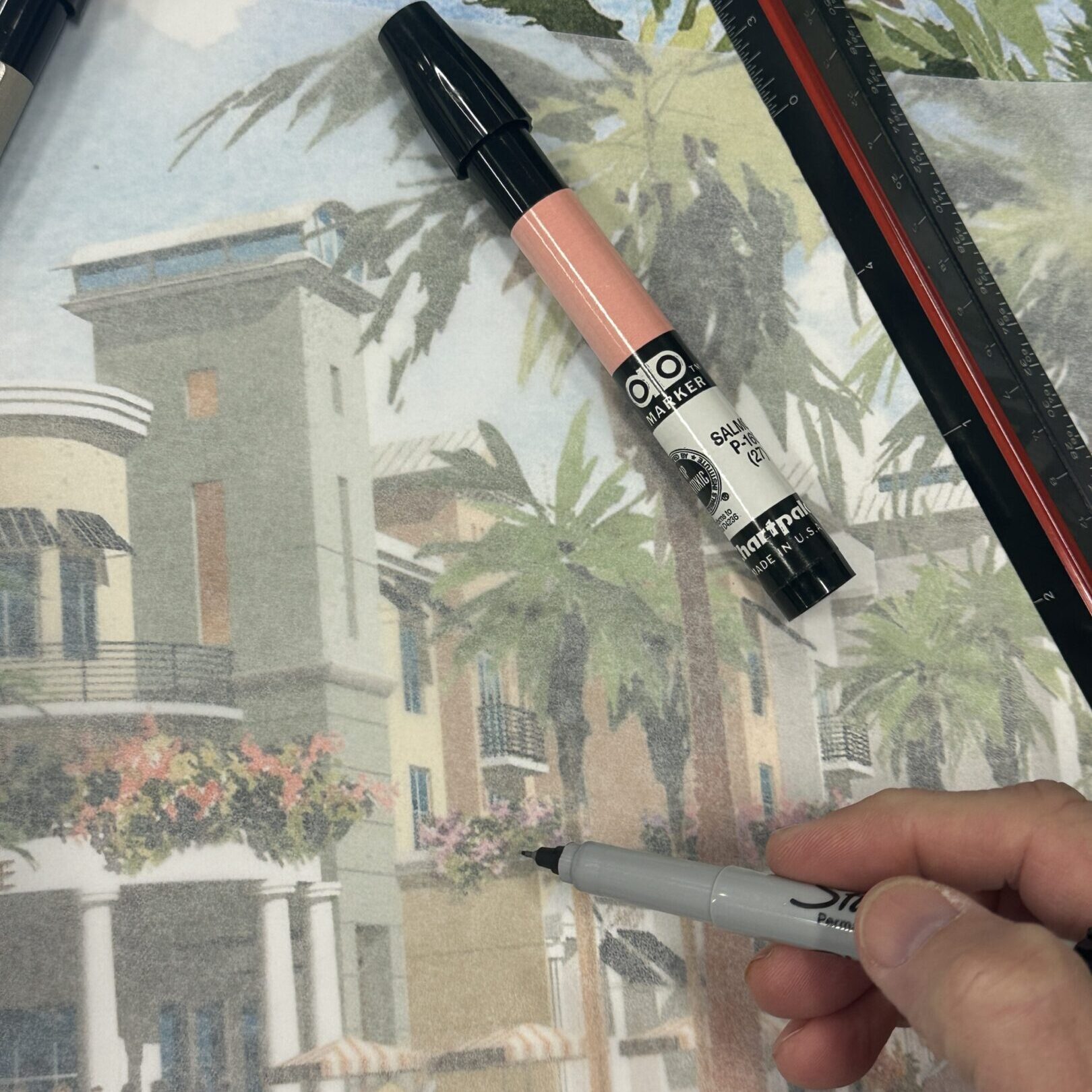 A hand drawing a realistic architectural sketch with a marker.